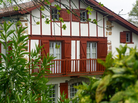 A traditional half-timbered house with a balcony surrounded by lush greenery