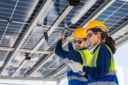 Engineers installing and inspecting solar panels on rooftop for renewable energy system, solar power technicians working together with tablet and multimeter on clean energy project