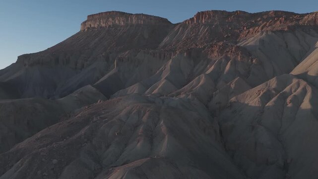 Sunlit desert mesa above sculpted gray ridges