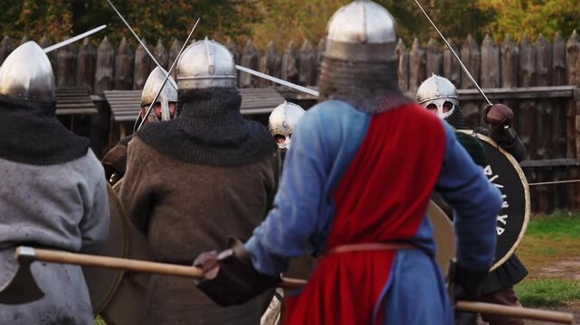 Viking warriors in full armor practicing combat drills with shields outdoors.