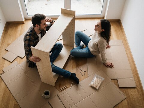 Happy couple assembling flat pack furniture at home