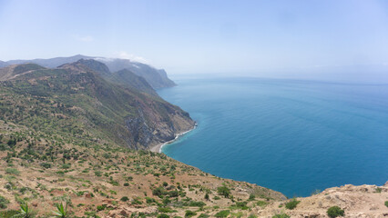Fototapeta premium Panoramic view of mountainous coastal cliffs meeting deep blue sea with outdoors