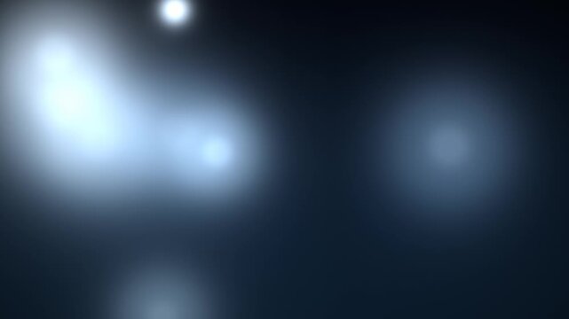 Light flares descend across a dark blurred background in a slow motion sequence flare illumination glow