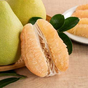 Fresh pomelo fruit with leaf on wooden table background.
