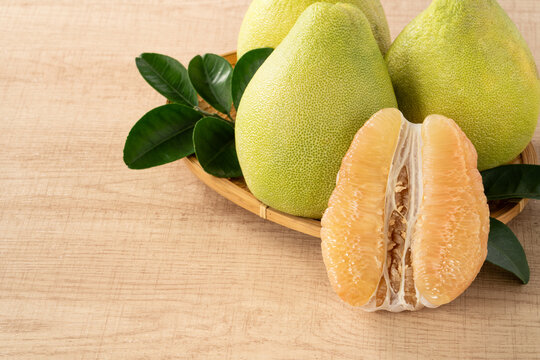 Fresh pomelo fruit with leaf on wooden table background.
