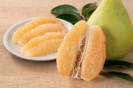 Fresh pomelo fruit with leaf on wooden table background.