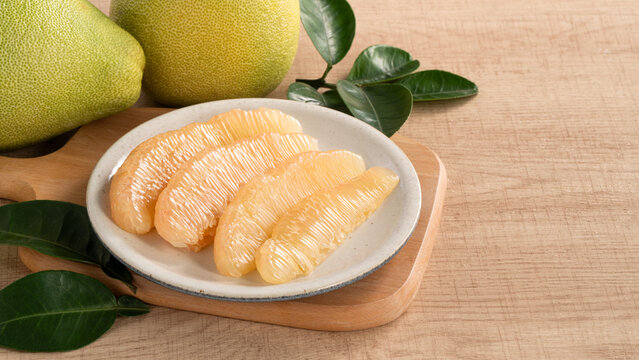 Fresh pomelo fruit with leaf on wooden table background.