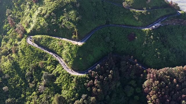 Drone aerial footage of motorcycle riders navigating scenic winding mountain roads on Mount Telomoyo in Central Java, Indonesia, showcasing adventure travel.