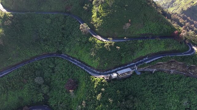 Drone aerial footage of motorcycle riders navigating scenic winding mountain roads on Mount Telomoyo in Central Java, Indonesia, showcasing adventure travel.