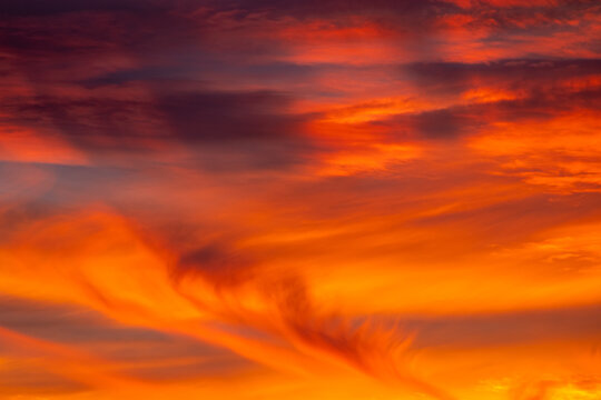 Vibrant sky filled with fiery red and orange cloud wisps glowing in the dusk light