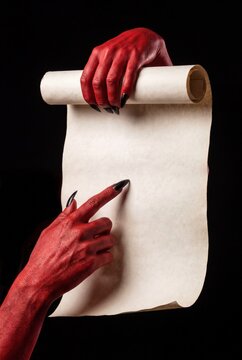 Red devil hands with black claws holding blank parchment scroll for Halloween message