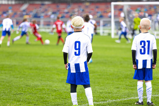 Junior Soccer Players in Blue and White Striped Shirts Numbers 9 and 31. Kids in Football Game Standing on Pitch Sideline. Soccer Torunament For School Boys