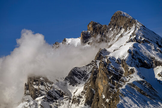 A snow-capped peak in the Swiss Alps emerging from the clouds