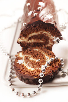 festive chocolate yule log cake slice with silver garland and bauble macro view