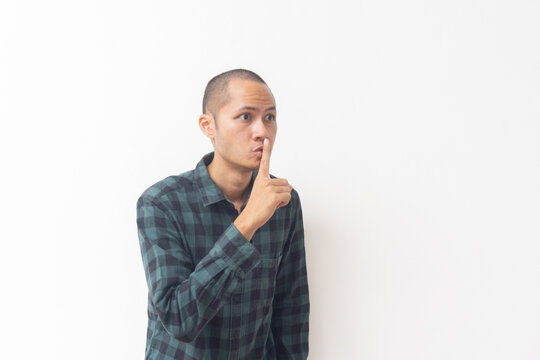 Asian man making silence gesture with finger on lips on white