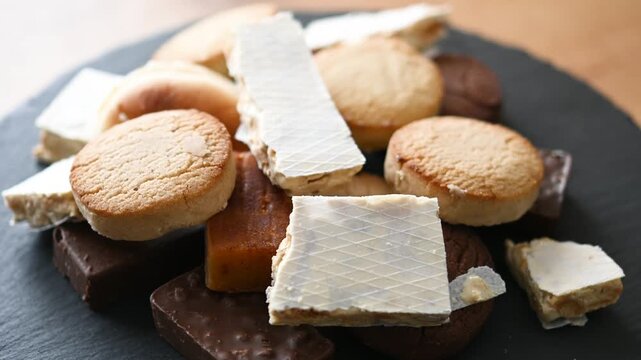 Close-up video of traditional Spanish turrones and polvorones rotating on a plate. Assorted festive sweets typical of Christmas in Spain presented as a seasonal holiday dessert.