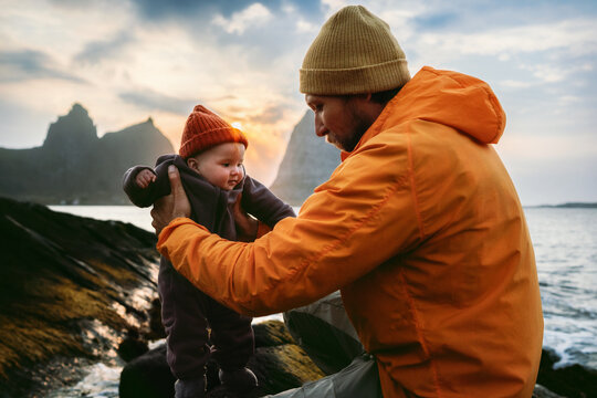 Baby and father playing outdoors family travel lifestyle dad carrying infant child, autumn vacations in Norway parent with kid walking together by sunset sea happy moment Fathers day holiday