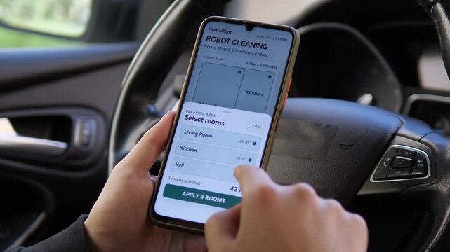 Person selects rooms for robot vacuum cleaning in a smart home app, highlighting automated housekeeping, connected living and remote control of domestic technology.