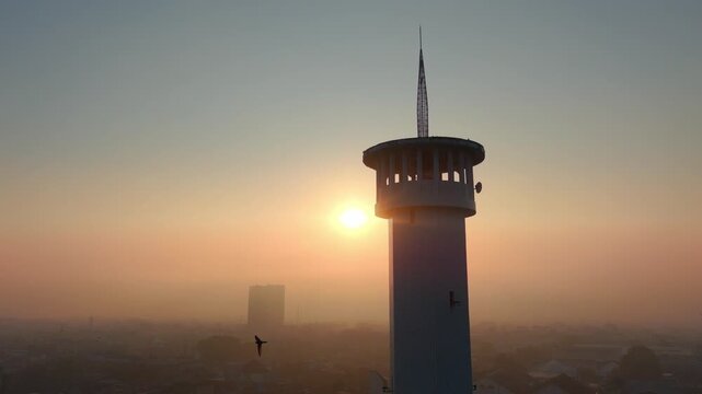 Aerial view of a tower at sunrise with hazy city skyline in the background in Malang, East Java, Indonesia.