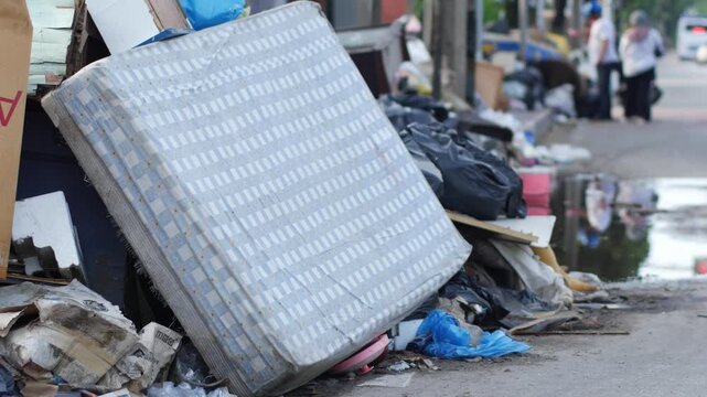 Discarded Mattress and Household Trash Piled on Street Curb, Urban Bulk Waste Scene