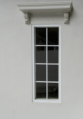 Elegant Tall Narrow Window with White Frames and Ornate Classical Cornice Detail on a Plain Stucco Wall for Architecture and Real Estate Concepts © ahsancreative