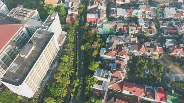 Aerial view of dense residential area with lush trees and buildings in Malang, East Java, Indonesia.