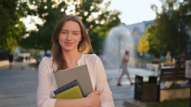Young Student Woman With Glasses Holding Notebooks On A Sunny Urban Street