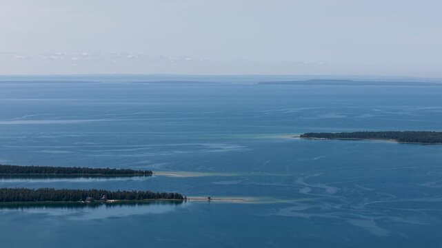 Wide aerial panorama of calm blue Lake Huron stretching beyond low wooded islands near Hessel in the Upper Peninsula of Michigan.