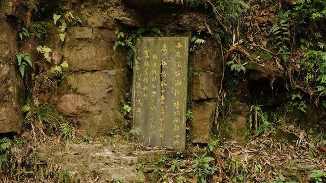 Chinese stone inscription stands beside a rocky forest path in Zhangjiajie.