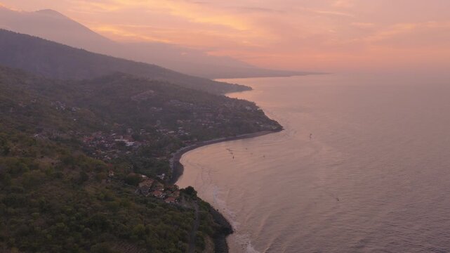 Sunset Over Pantai Jemeluk Bay Coastline With Mount Agung Silhouetted In Amed, Bali, Indonesia. - aerial shot