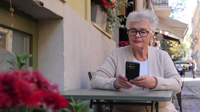 Older woman talking on video call using smartphone at cafe. Online communication, digital inclusion, technology for seniors and connected lifestyle