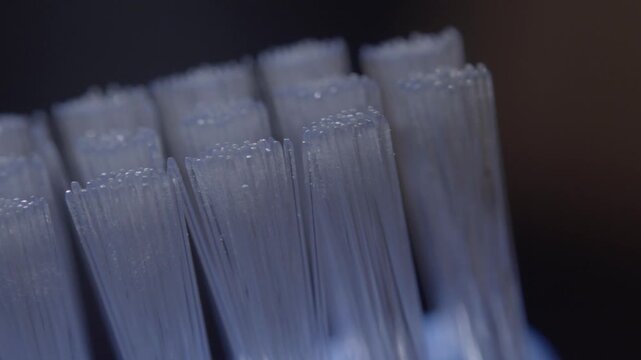 Panning macro view of blue toothbrush bristles showing dense nylon fibers and detailed texture. Close up movement reveals rows of soft bristles used for daily dental hygiene and cleaning.