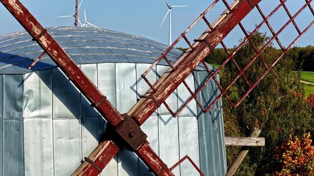 Aerial view of a historic windmill at Pakruojis Manor with weathered red wooden blades and a metallic dome roof set against a clear blue sky in Pakruojis, Siauliu apskritis, Lithuania.