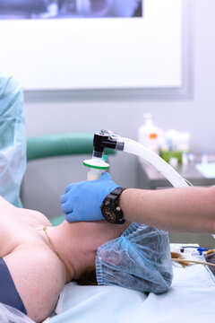 Anesthesiologist holds face mask of anesthesia machine on patient. Oxygen and anesthetic delivered through breathing circuit