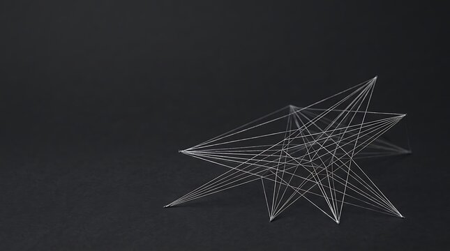 Silver thread geometric star sculpture on a dark charcoal background