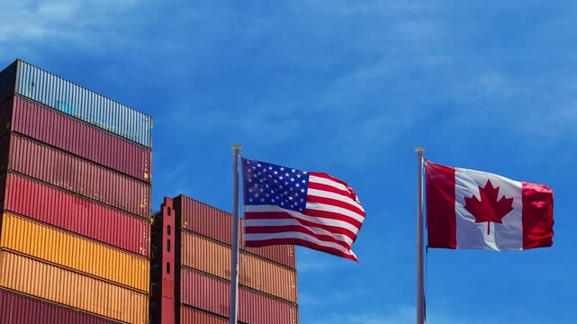 United States and Canada flags waving in front of cargo shipping containers under blue sky. 4K video representing US and Canadian international trade, export, and logistics relations.