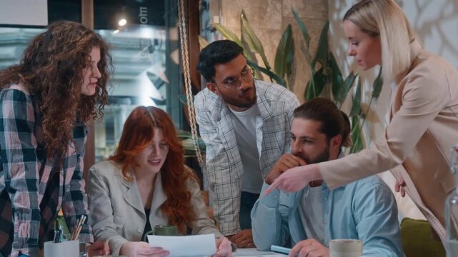 Casual informal business team five creative coworkers discussing papers documents in office startup project result paperwork talking together multiracial colleagues discuss work meeting collaboration