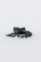 Fototapeta premium Toy military tank driving through snow with vertical copy space.