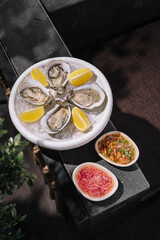 Fresh oysters on ice with lemon and mignonette sauces © AntAlexStudio