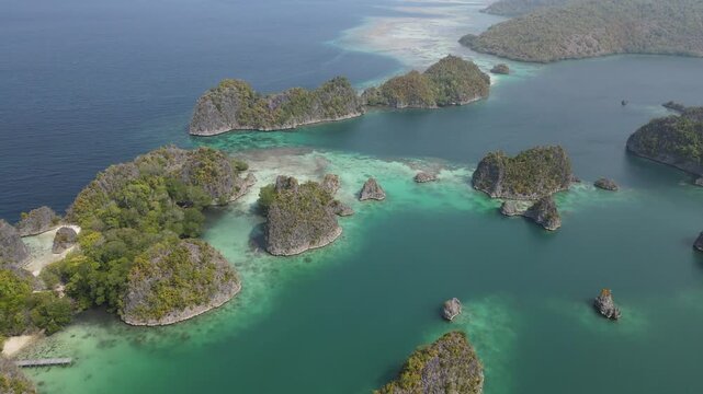 Aerial view of Piaynemo karst islands surrounded by turquoise waters and lush vegetation in Raja Ampat, Southwest Papua, Indonesia.