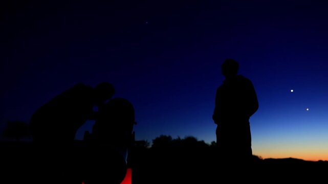 Amateur astronomers observing stars, planets, Moon and other celestial objects with a telescope in nature.