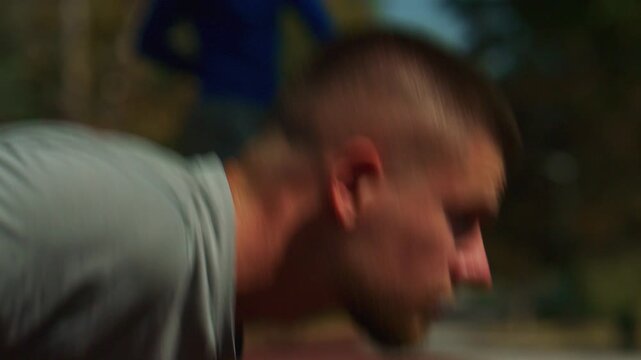 An athletic man takes a ready position on a running track. He shows focus and determination before starting his sprint.