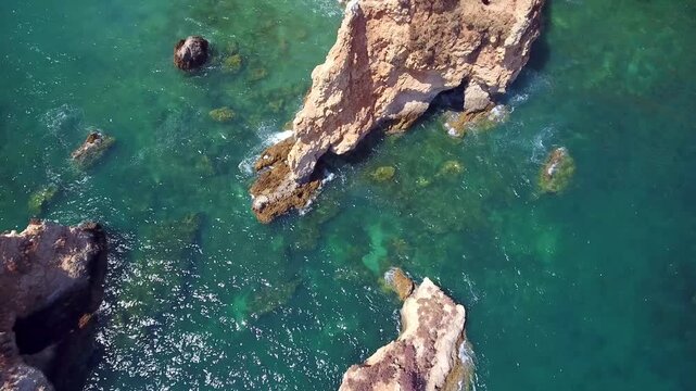 Stunning top down aerial view of the praia do alemao rocky coastline in portimao, portugal, with its iconic cliffs and sea stacks emerging from the turquoise waters of the atlantic ocean