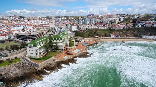 Magnificent aerial view of the coastal town of ericeira in portugal, featuring the iconic baleia beach and powerful ocean waves crashing against the rocky shoreline on a sunny day