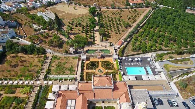 Majestic aerial view slowly descending over the stunning rococo architecture and formal gardens of the historic estoi palace, a luxurious hotel and landmark in the sunny algarve region of portugal