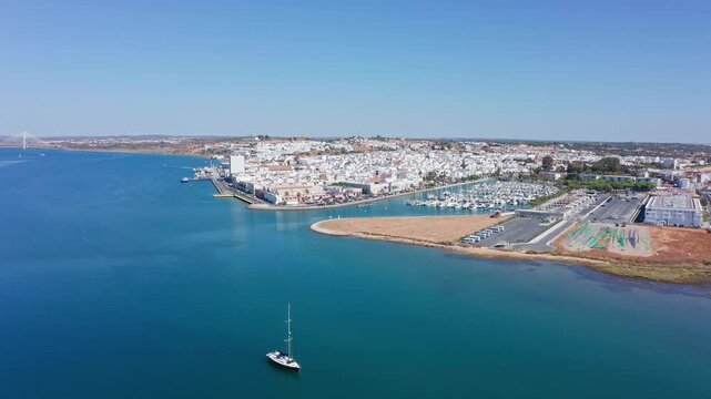 Stunning aerial footage revealing the beautiful coastal town of ayamonte, its bustling marina, and the tranquil guadiana river under a clear blue sky on the border between spain and portugal