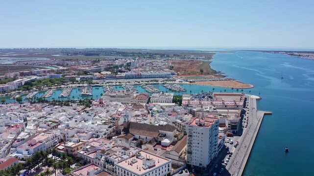 Aerial footage showing the charming coastal town of ayamonte in andalusia, spain, with its characteristic white houses, marina, and the vast expanse of the guadiana river on a sunny day