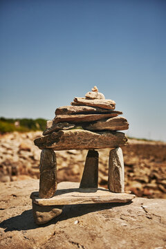 balanced stone sculpture, aka rock stack or cairn, built on a larger coastal rock under a clear blue sky, Peaks Island, Maine, New England 