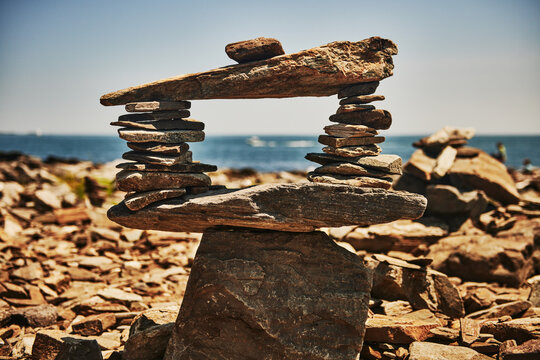 balanced stone sculpture, aka rock stack or cairn, built on a larger coastal rock under a clear blue sky, Peaks Island, Maine, New England 