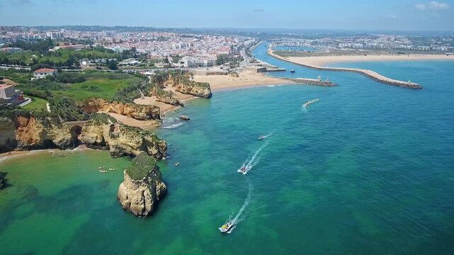 Stunning aerial perspective of the algarve coastline featuring limestone cliffs, turquoise water, and tour boats sailing near the picturesque city of lagos on a beautiful sunny day